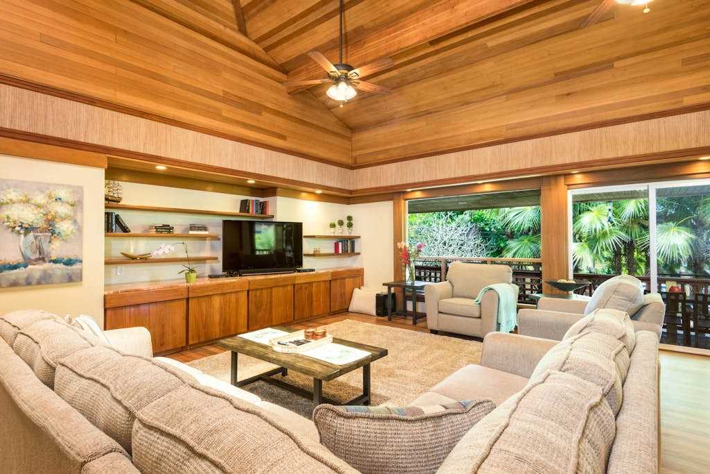 Open living room showcases wood ceilings, seating, and garden views