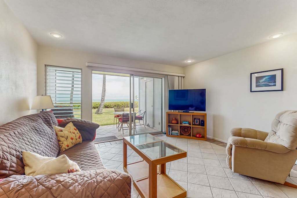 Living room features sofa, armchairs, television, coffee table, and windows