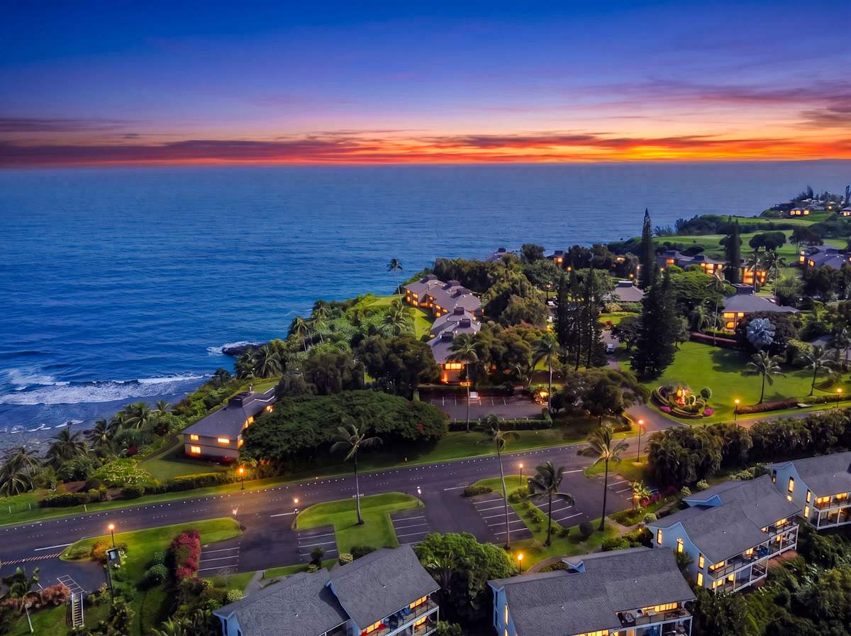 Coastal sunset creates a breathtaking backdrop above tropical homes and palms