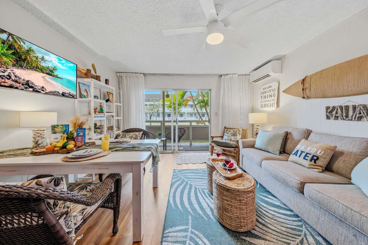 Bright living room with plush sofa, TV, surfboard decor & patio access