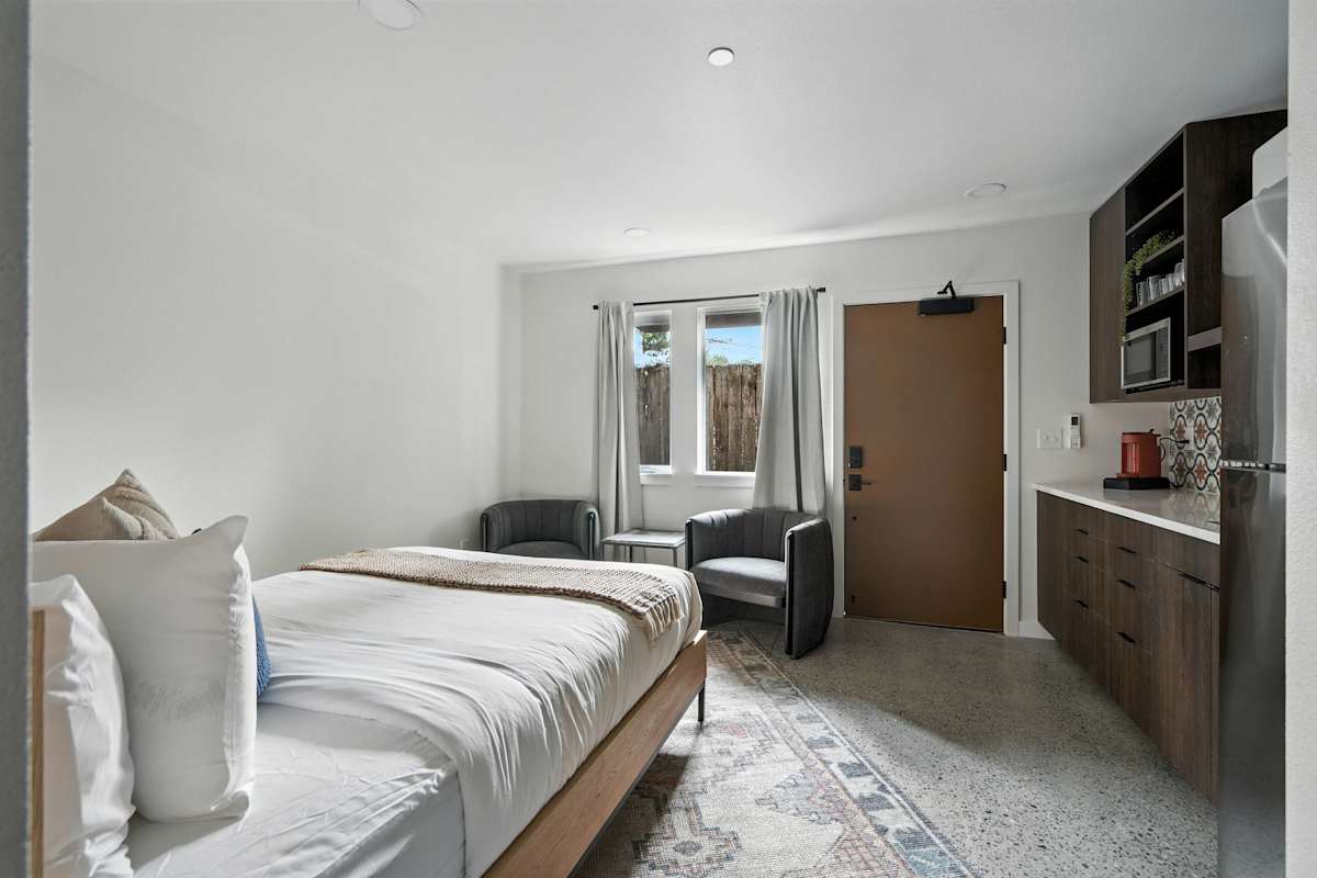 A hotel room with a bed, kitchenette, and sitting area