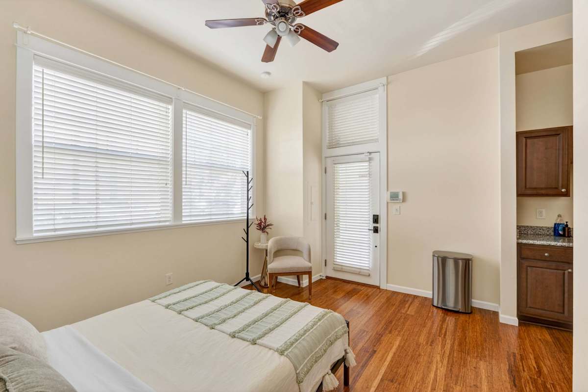 A wide view of a hotel room with a bed, chair, and kitchenette.