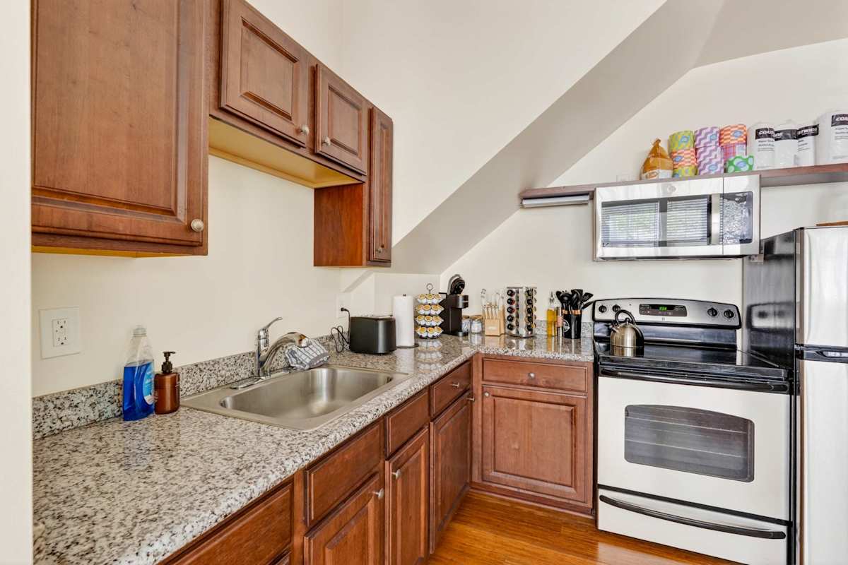 A kitchen with granite countertops, wooden cabinets, and white appliances.