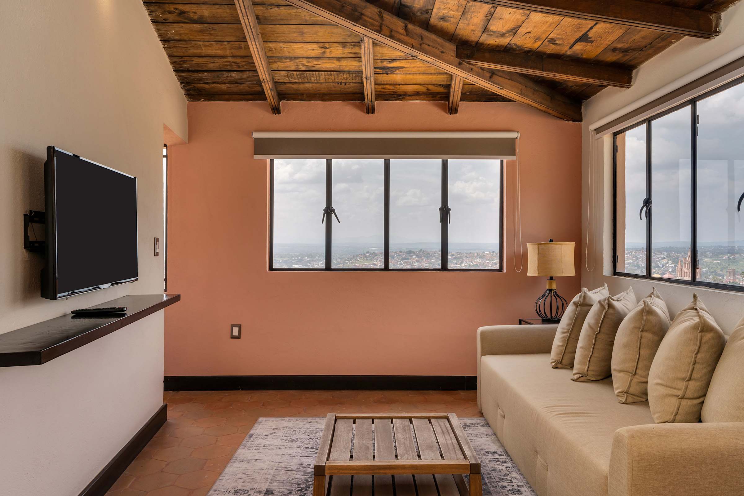 Living room sofa bed with a wall mounted TV and window views