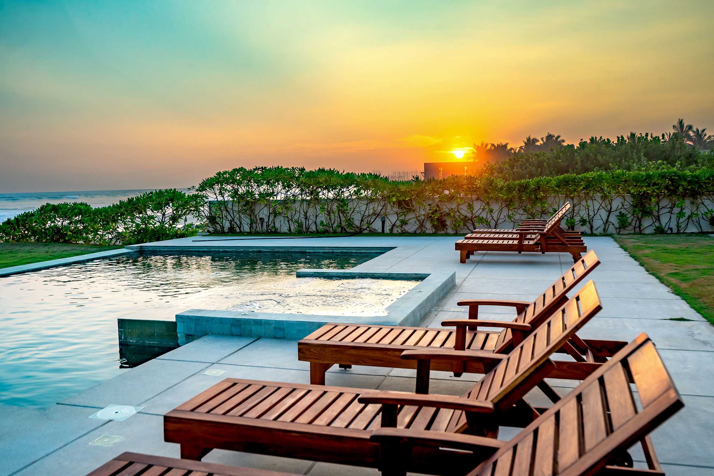 Golden sunset over the infinity pool with sun loungers — unwind as the sky turns brilliant shades of orange and gold