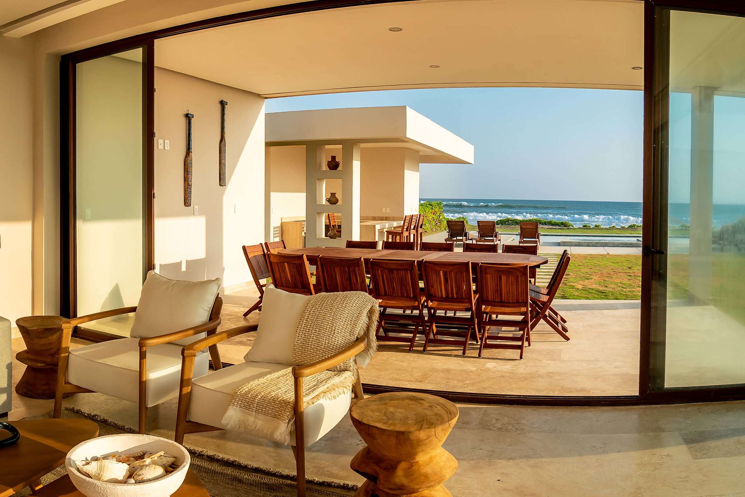 Chic indoor-outdoor lounge with woven rattan chairs and a terrace that frames panoramic ocean vistas