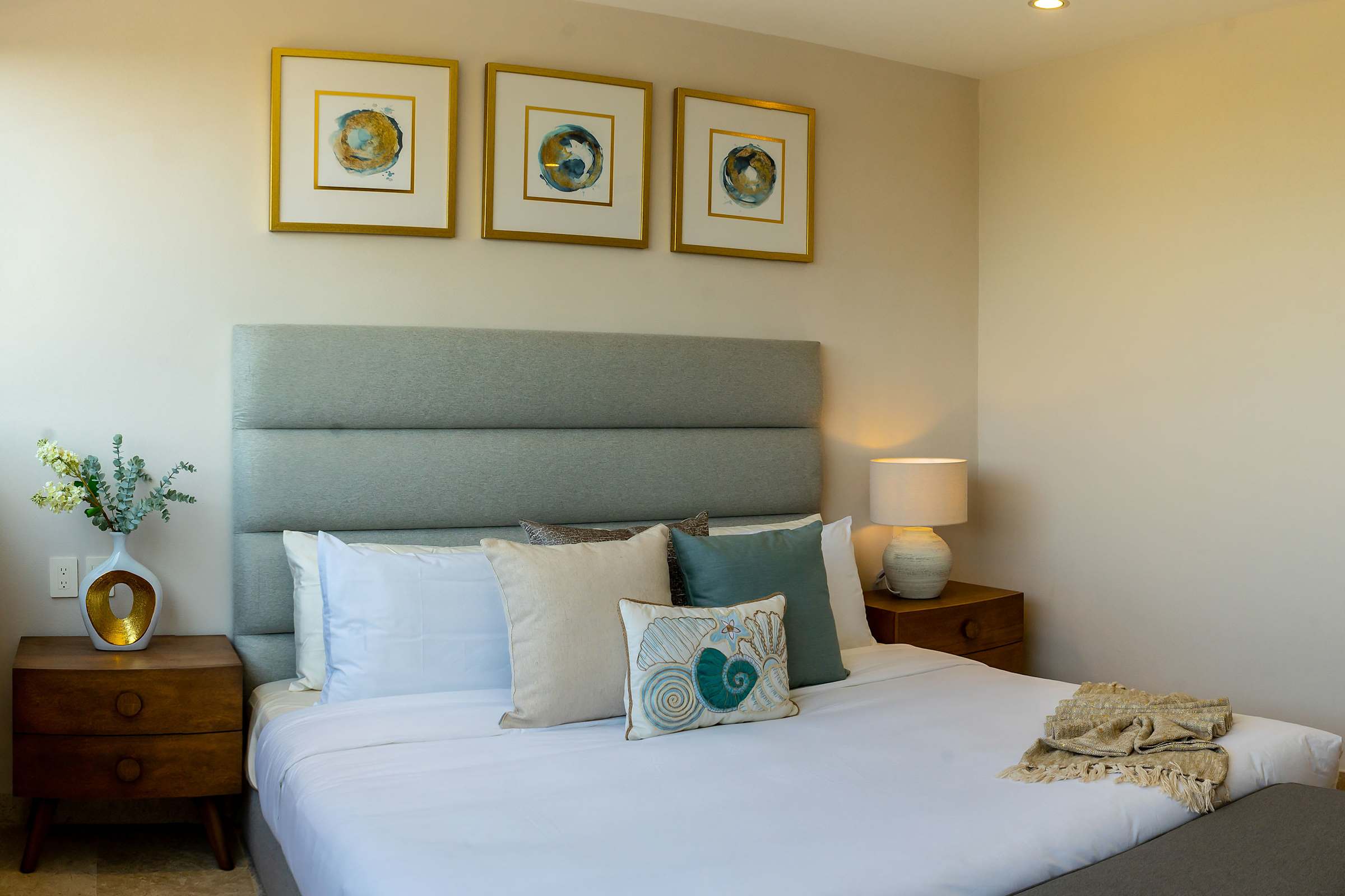 Bedroom 3 with a plush king bed, tropical botanical artwork, and warm ambient lighting