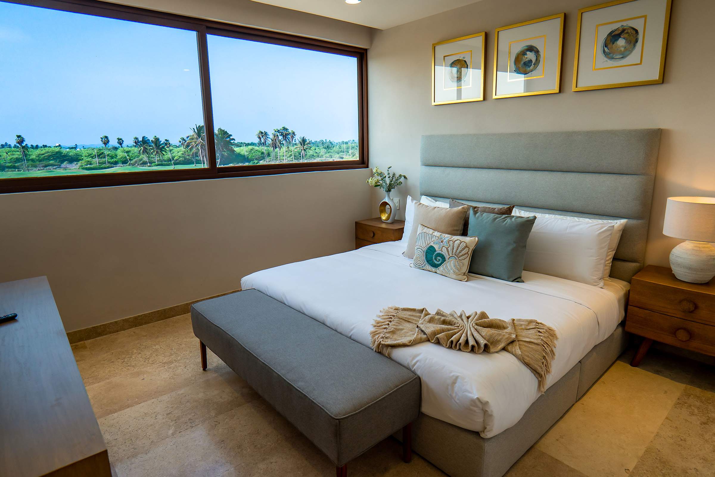 Bedroom 3 showcasing the king bed, warm lighting, and tropical greenery outside the window
