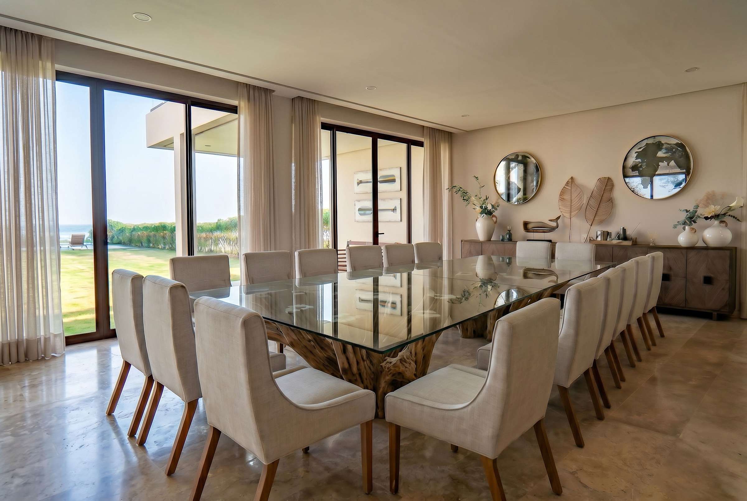 Grand formal dining room, sculptural mirrors, and walls of glass overlooking the pool and beach. Includes seating for up to 18