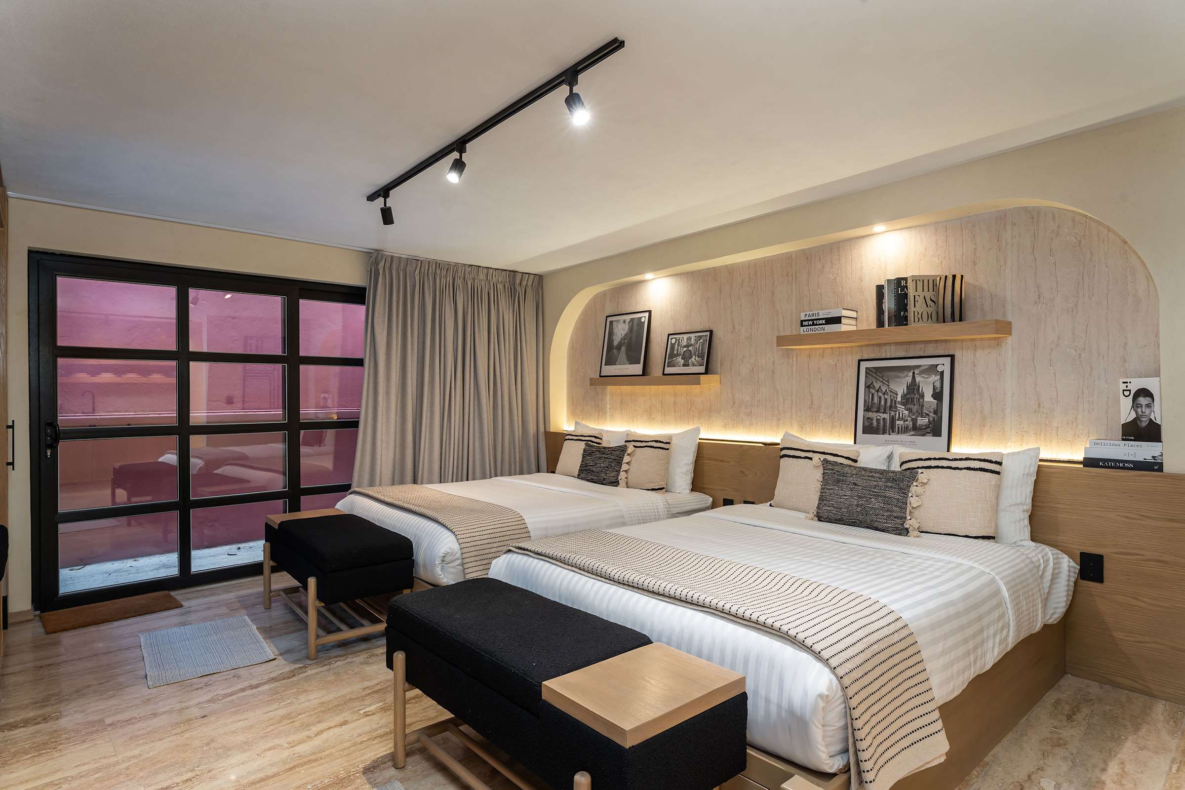 Bedroom showcasing the arched wood accent wall with floating shelf, and the open, airy layout of the room; featuring blackout shades.