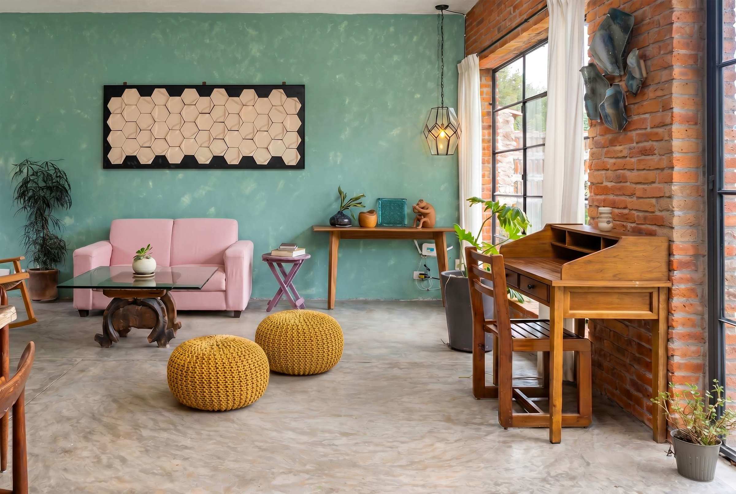 Open living room with pink sofa, curated artwork, exposed brick wall, and dedicated workspace desk