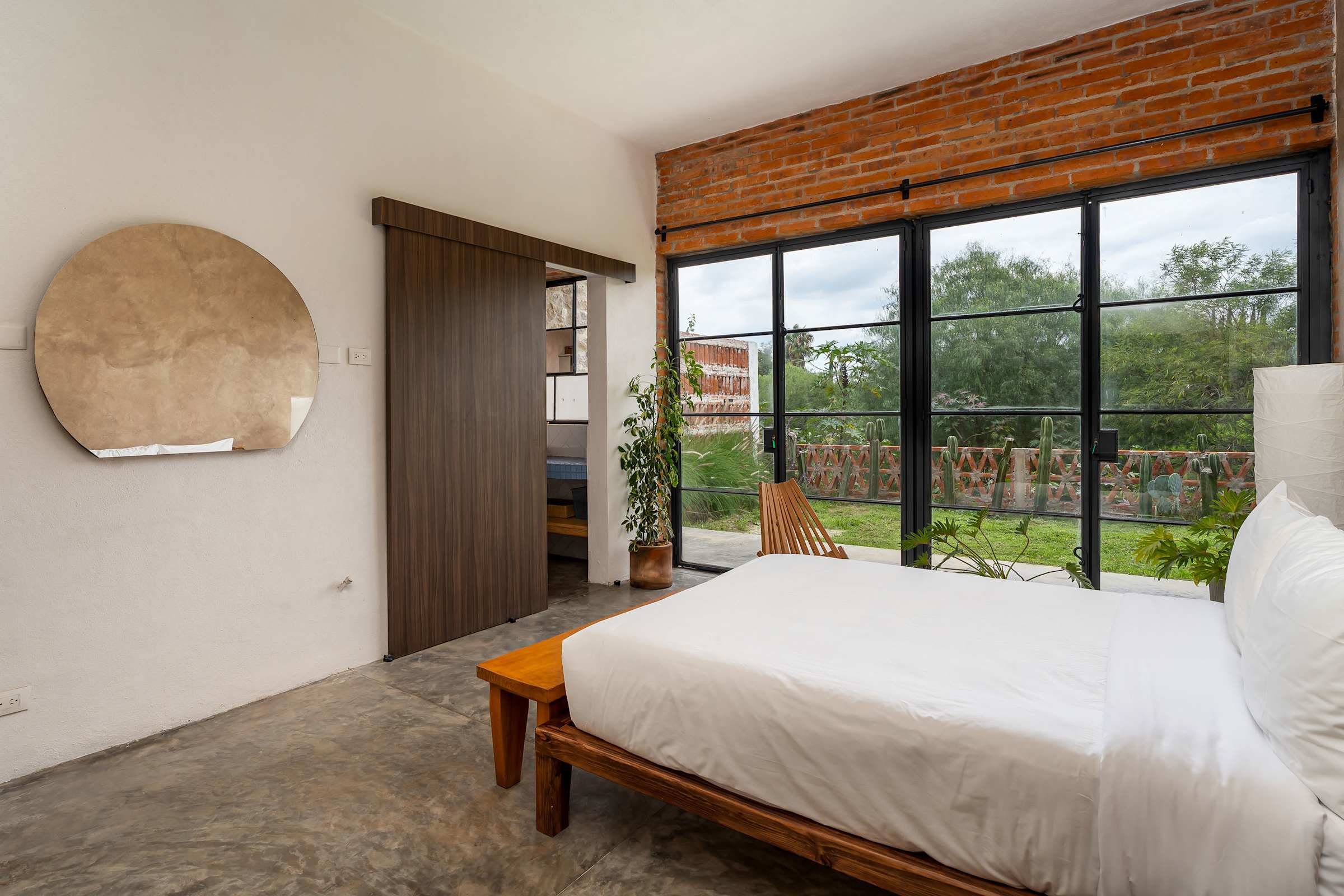 Queen bedroom with oversized windows, natural light, and views of the private garden