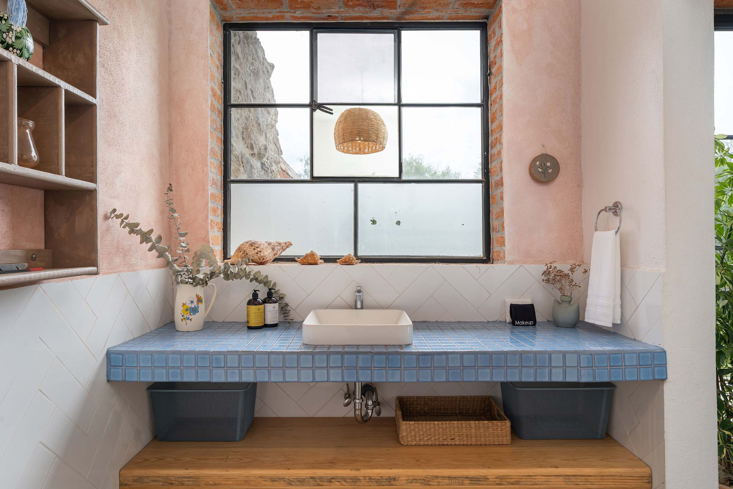 Bathroom vanity with blue mosaic tile counter, rattan pendant light, and open wood shelves