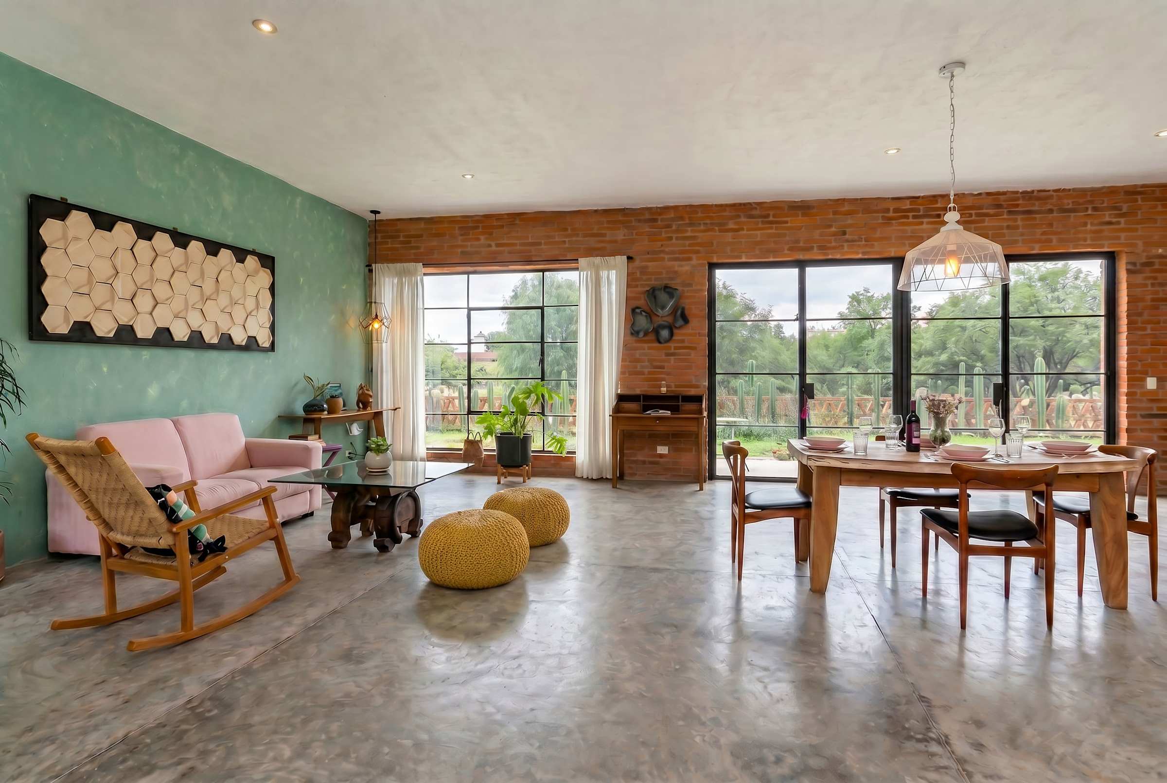 Bright open living and dining room with oversized garden windows, concrete floors, and pendant lighting