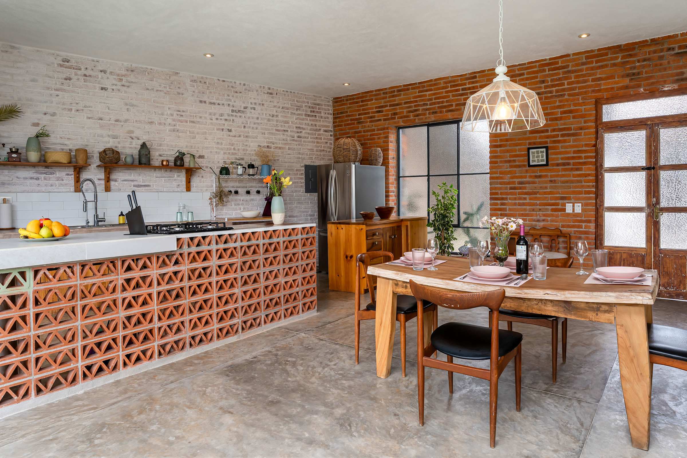 Open-plan kitchen with decorative brick island and dining table set