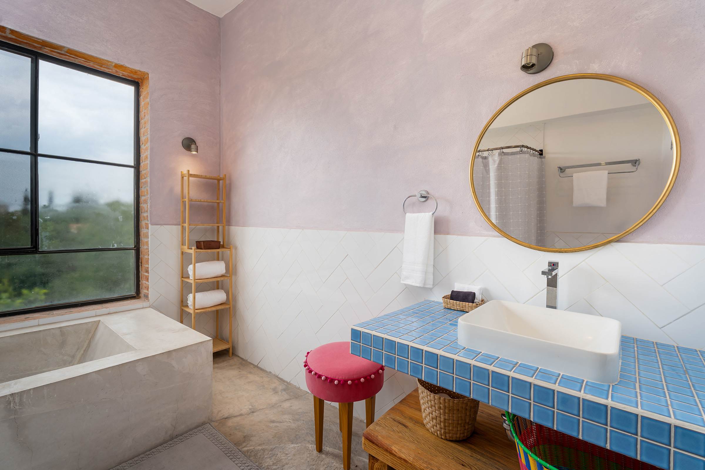 Spa-inspired bathroom with deep soaking tub, blue tile vanity, and round mirror