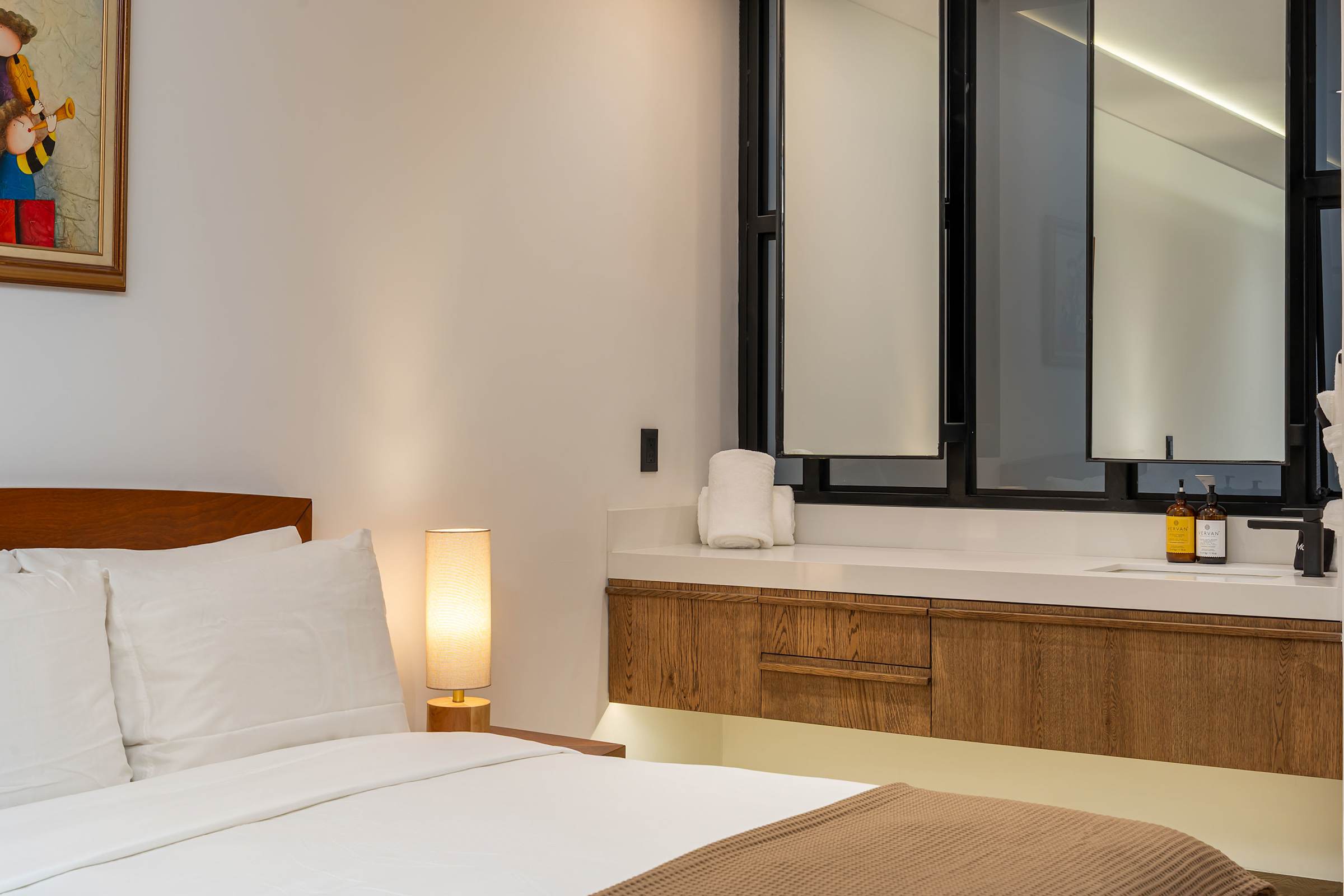 Bedroom nightstand and vanity with modern bathroom beyond