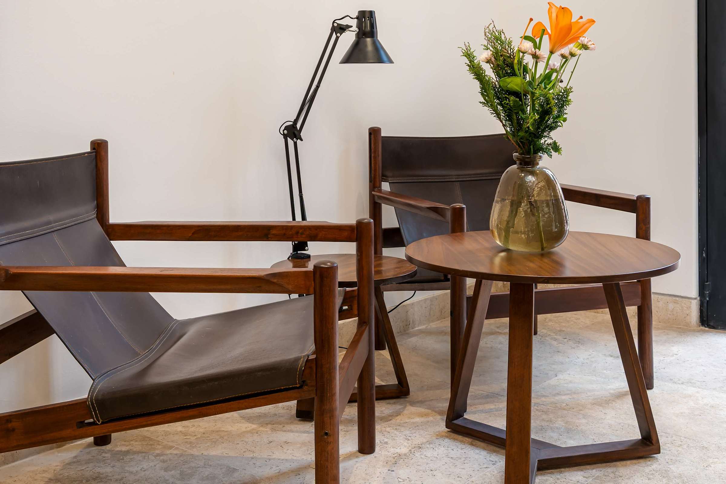 Seating area with wood-framed chairs, round coffee table, and lamp