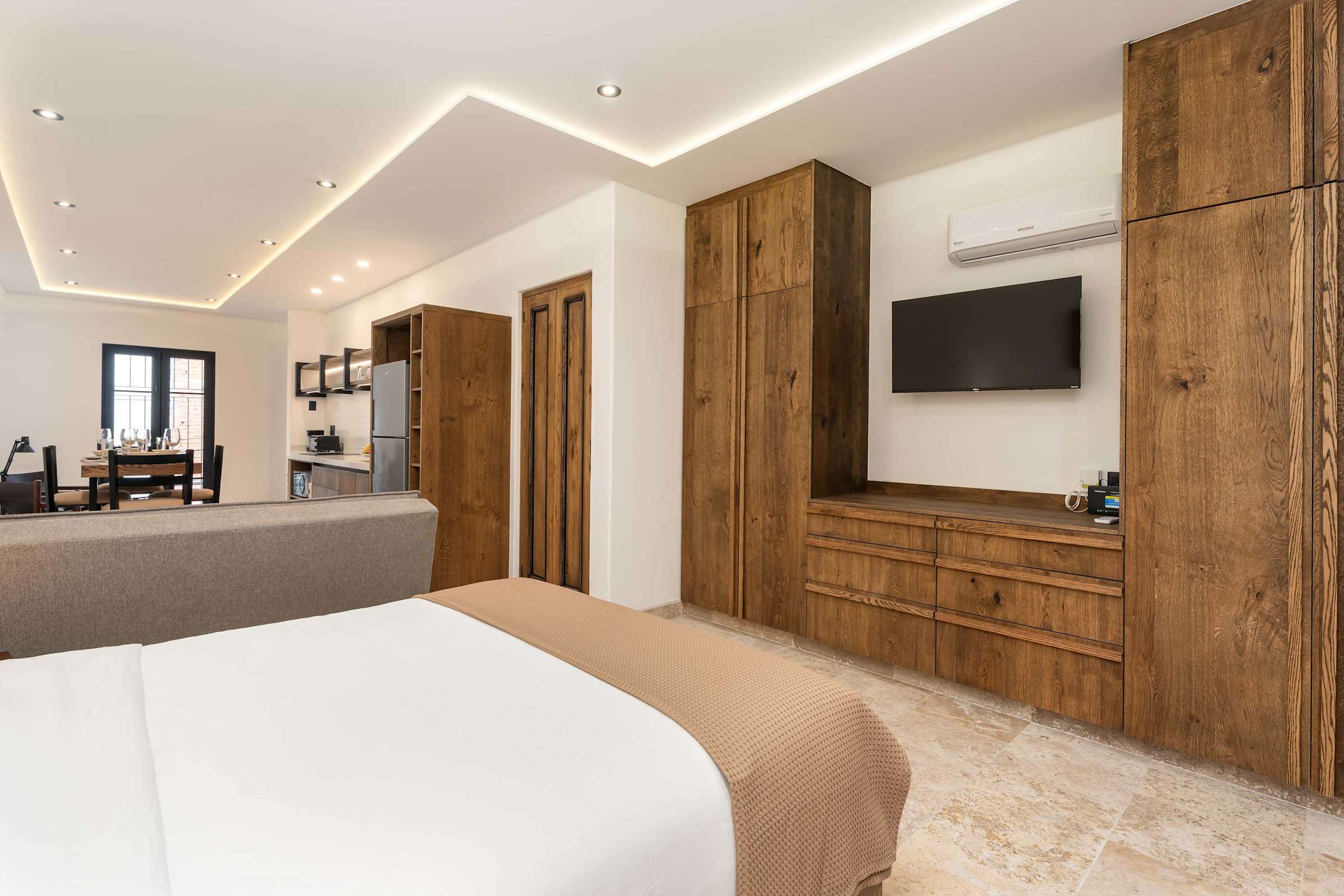 Open-plan living and bedroom area with wood wardrobe, TV, and AC