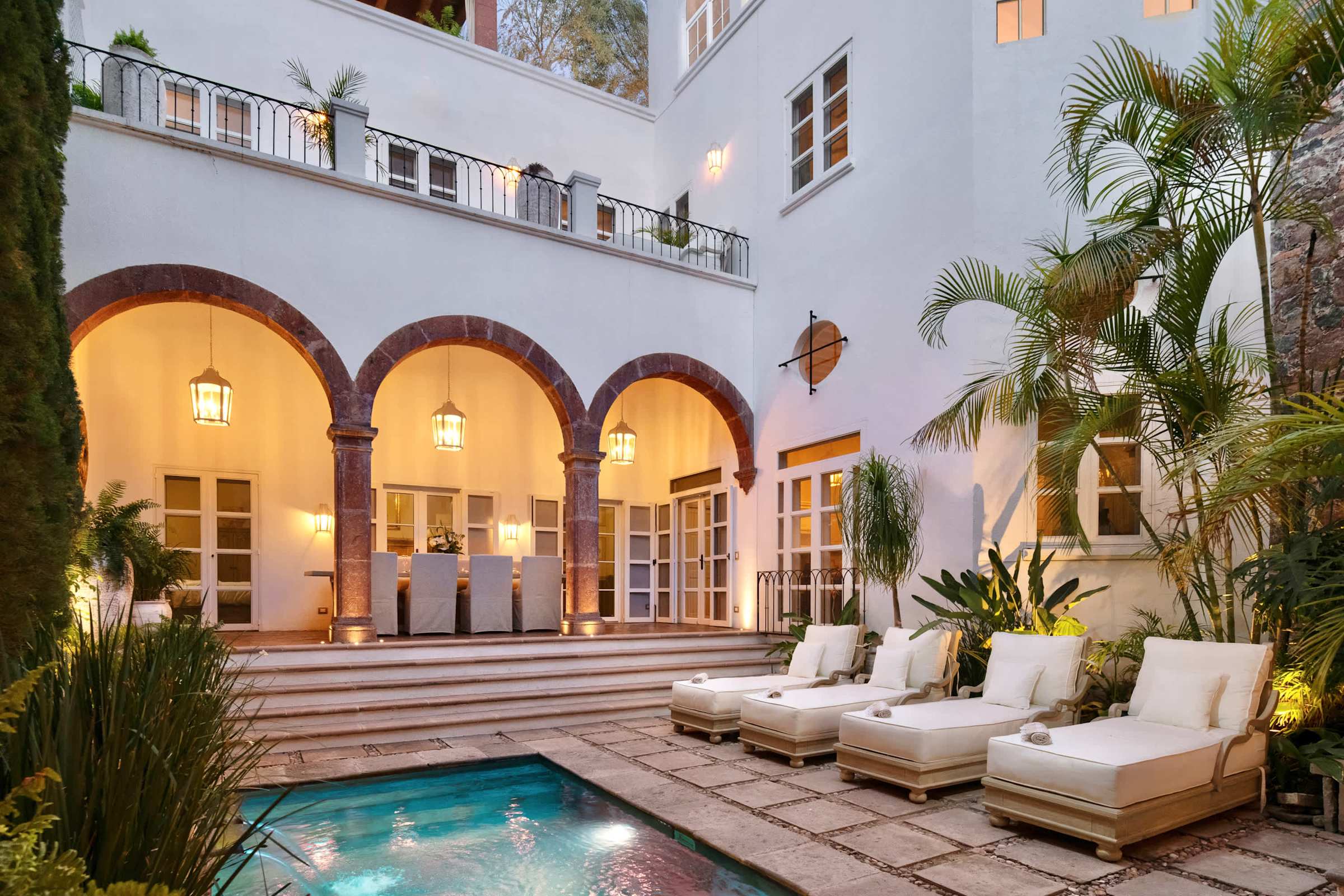 Courtyard pool with lounge seating, lit up in the evening