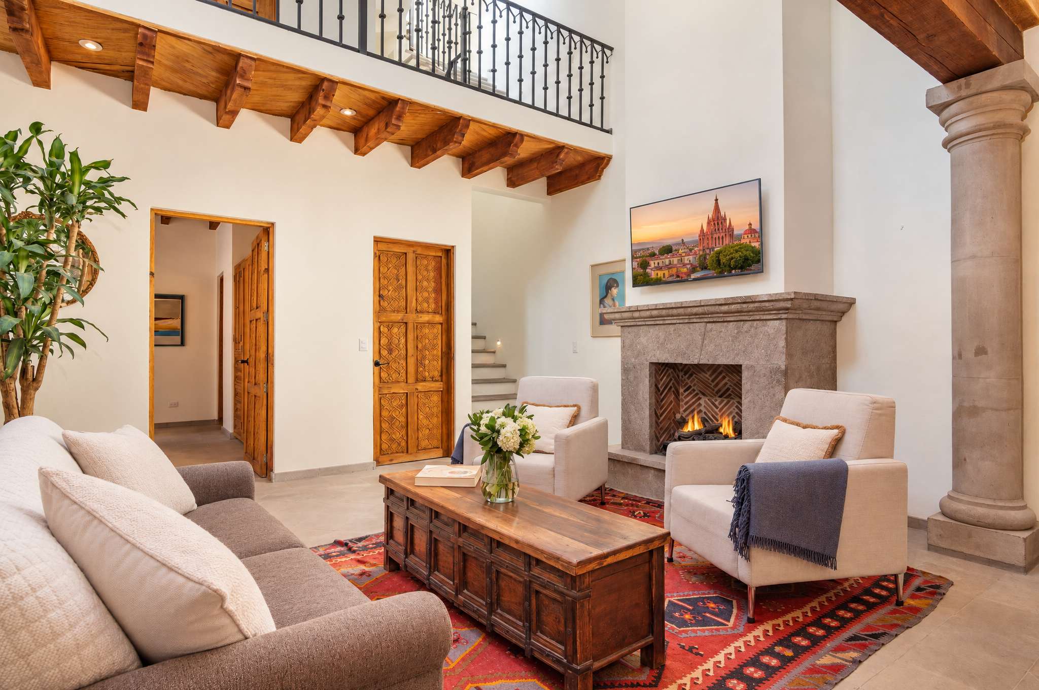 Sala con chimenea, vigas de madera, muebles cómodos y mezanine arriba