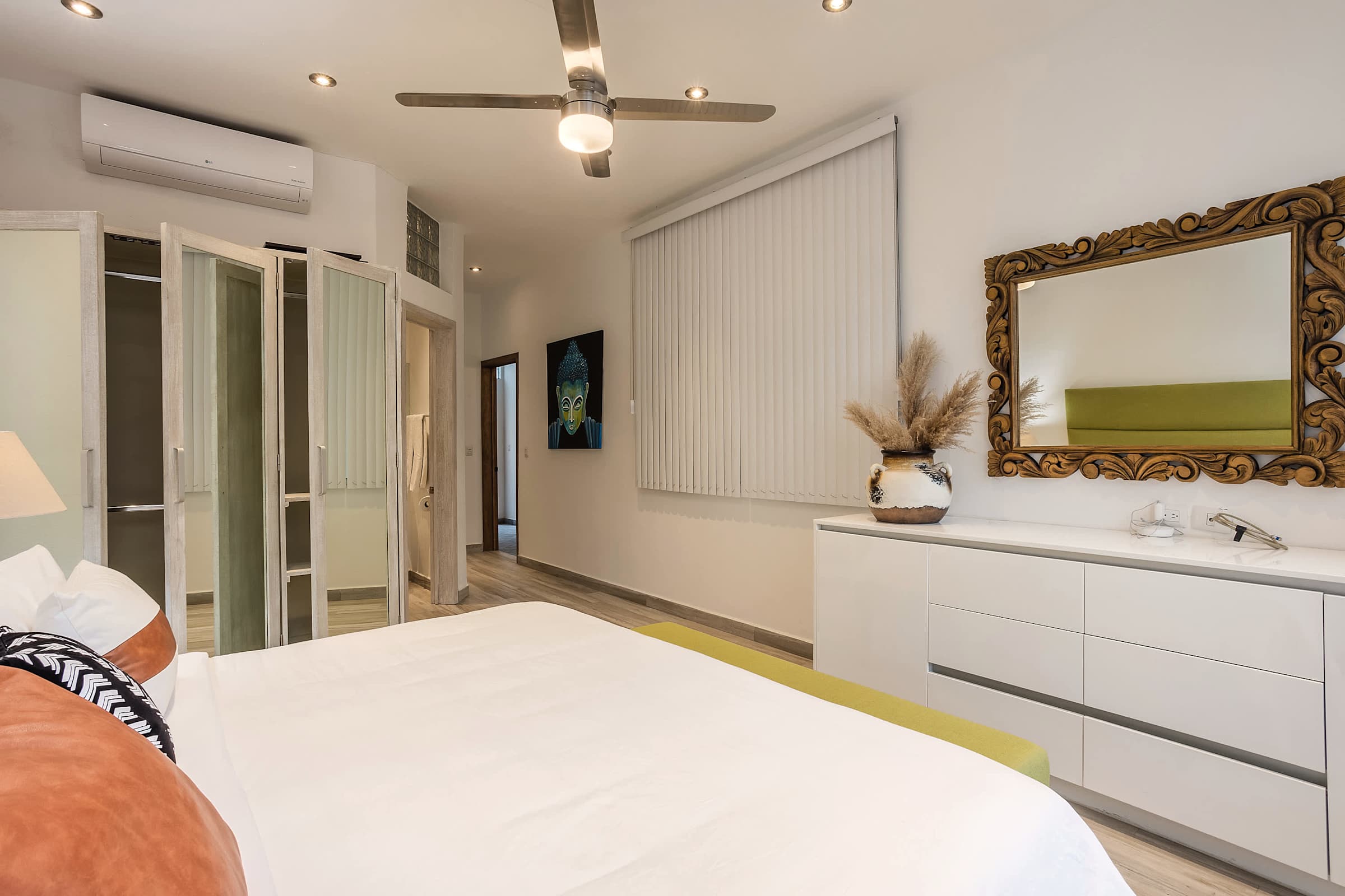 Recámara con tocador blanco, espejo tallado y closet empotrado con interior verde