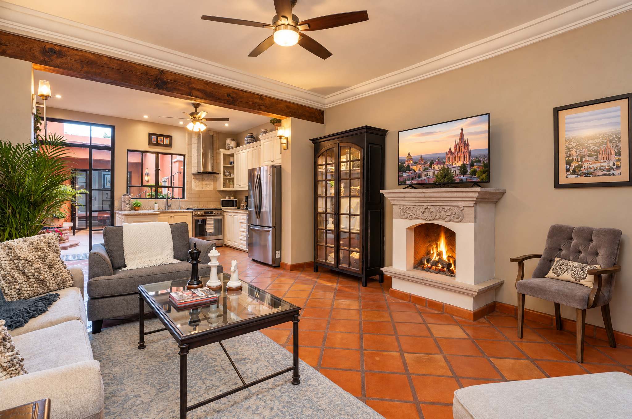 Living room with fireplace, gray armchairs, and views toward the kitchen and courtyard