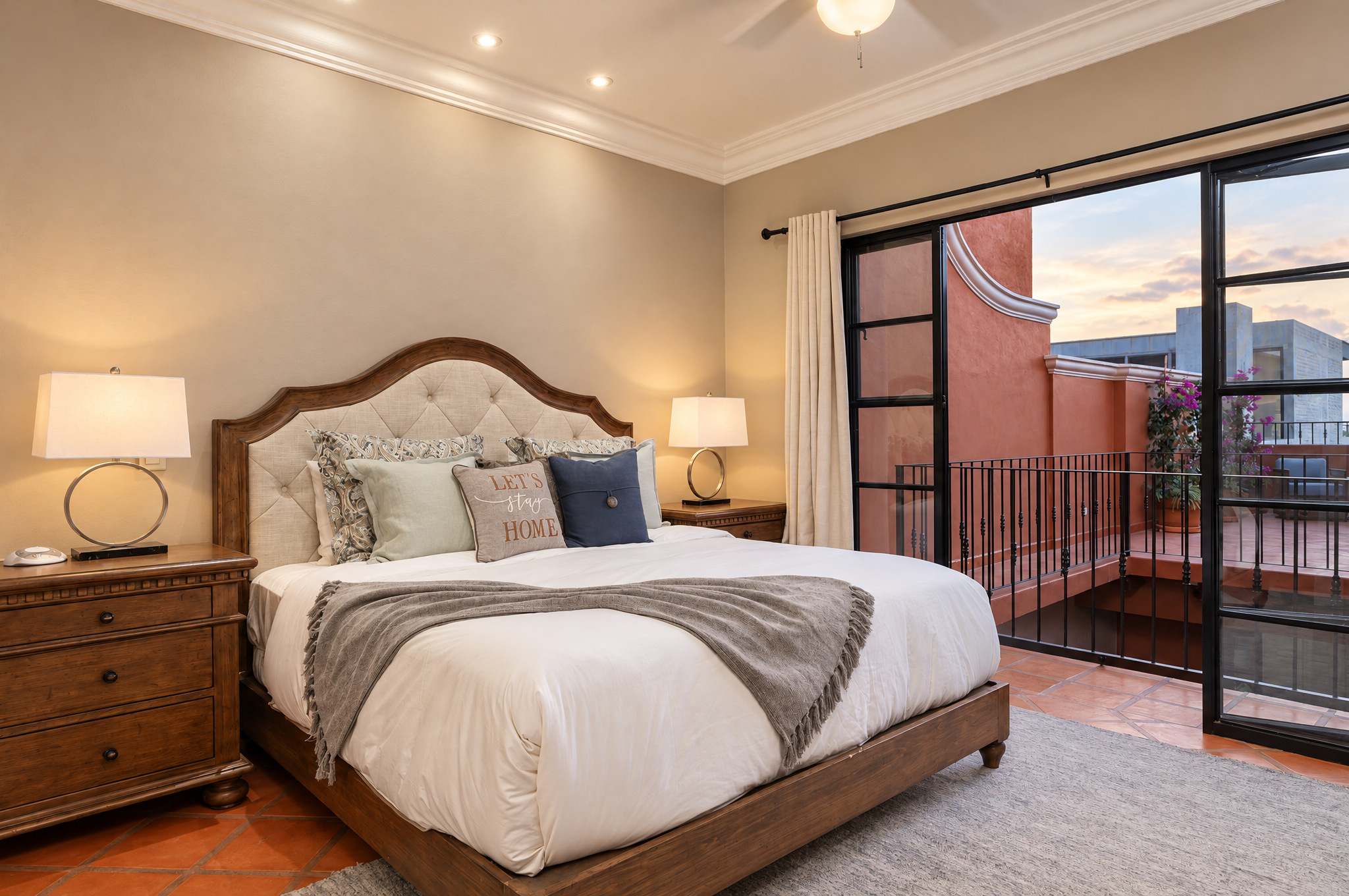 Master bedroom with wood bed, white linens, and glass doors opening to a city view balcony