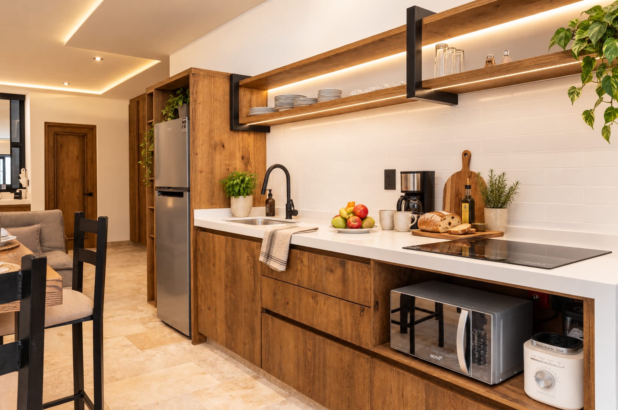Cocina moderna con gabinetes de madera, azulejos blancos en la pared y repisa abierta sobre electrodomésticos de acero inoxidable