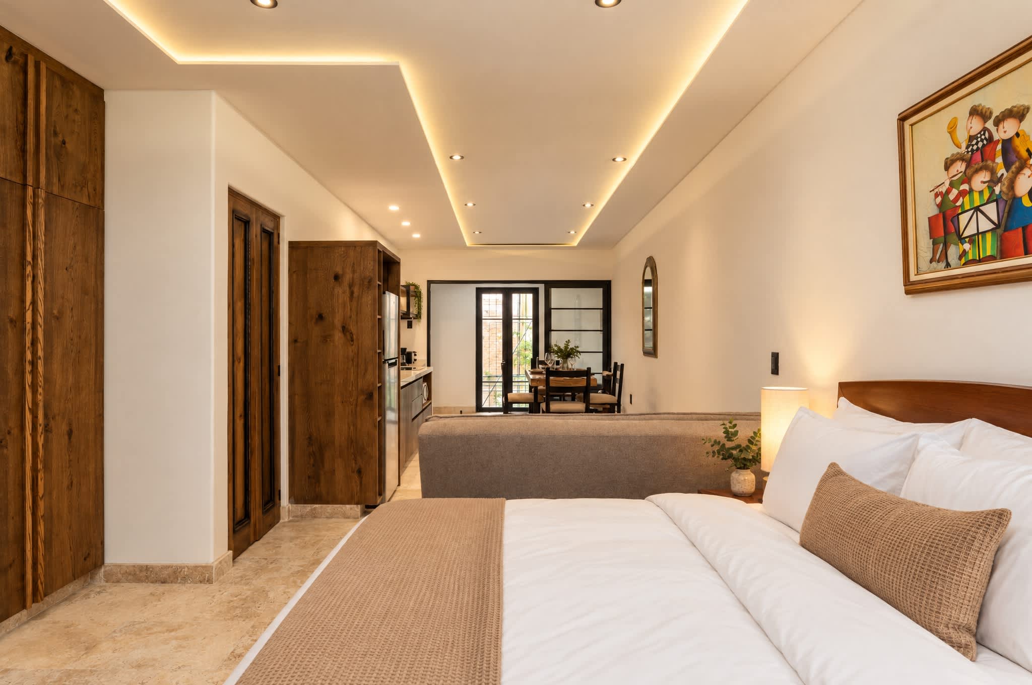 Recámara moderna con closets de madera, iluminación geométrica en el techo y área de estar abierta al fondo