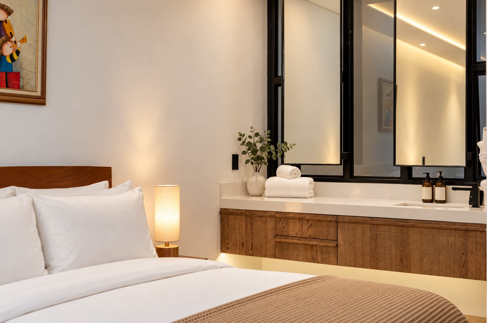 Rincón de recámara con cama, tocador de madera, espejo grande e iluminación cálida