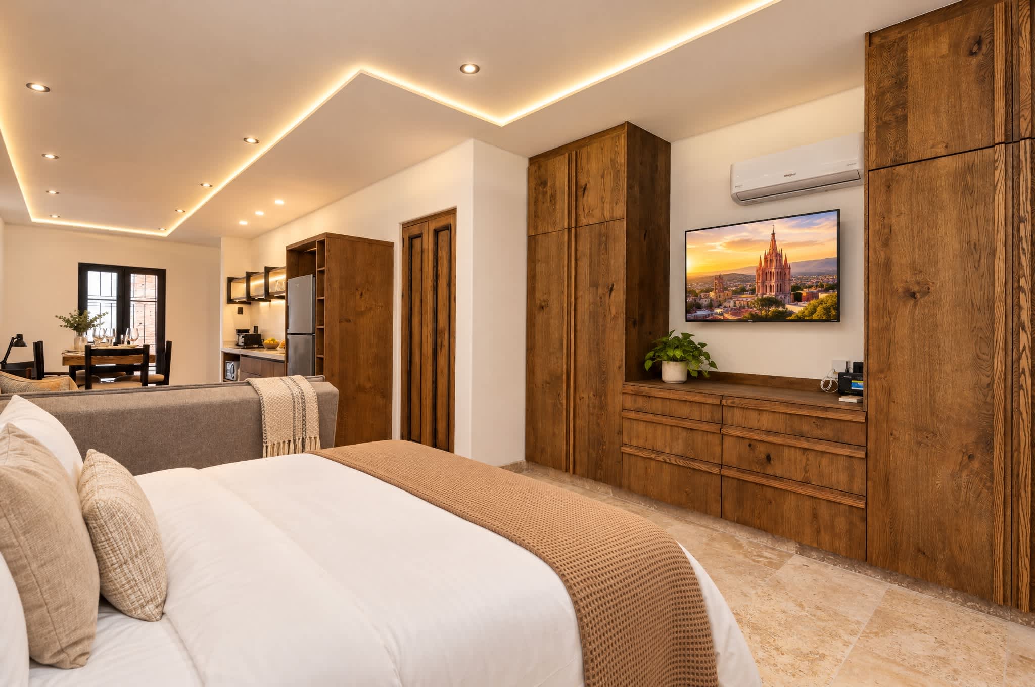 Recámara moderna con cama queen, muebles de madera y TV montada mostrando la Parroquia