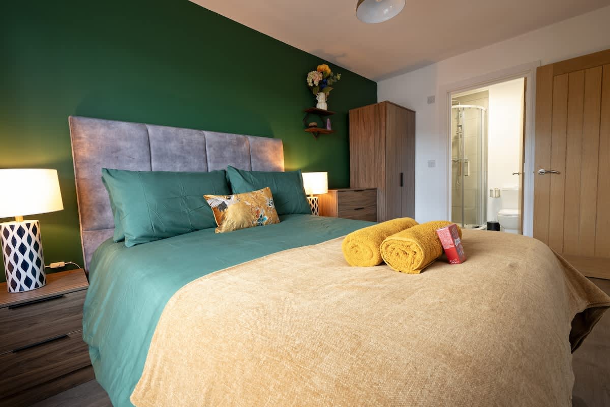 King bedroom with statement green wall and upholstered bed
