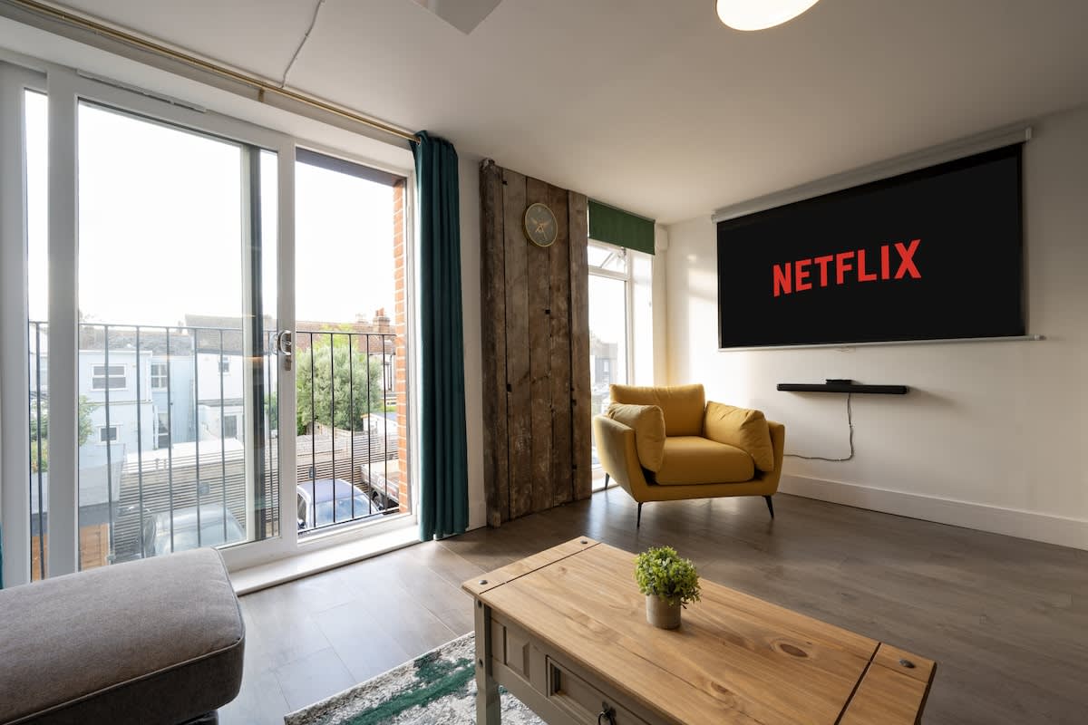 Living area with sliding doors leading onto the balcony, Netflix-ready Projector