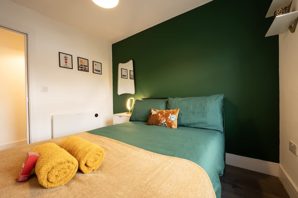 Double bedroom with green accent wall and soft furnishings