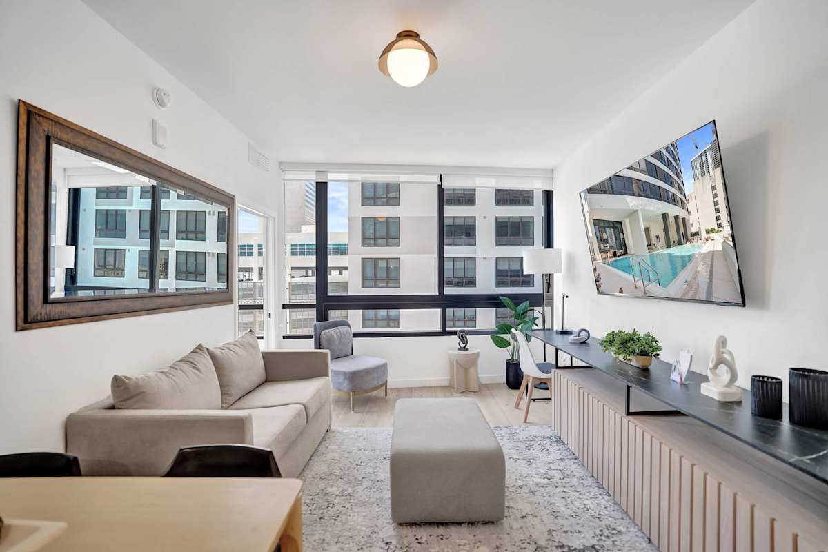 Bright and modern living area with large windows, city views, and a cozy, stylish setup perfect for relaxing.