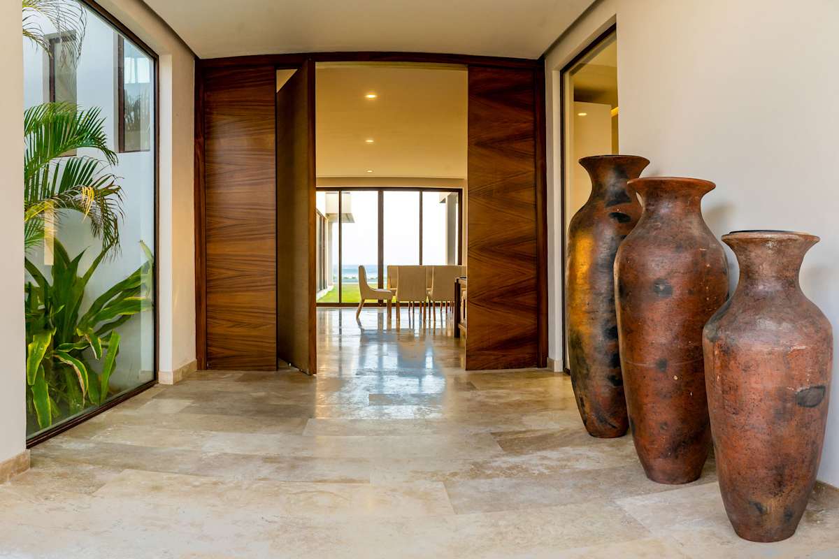 Grand villa foyer with dramatic clay-jar sculptures, glossy marble floors, and a striking wooden entry door
