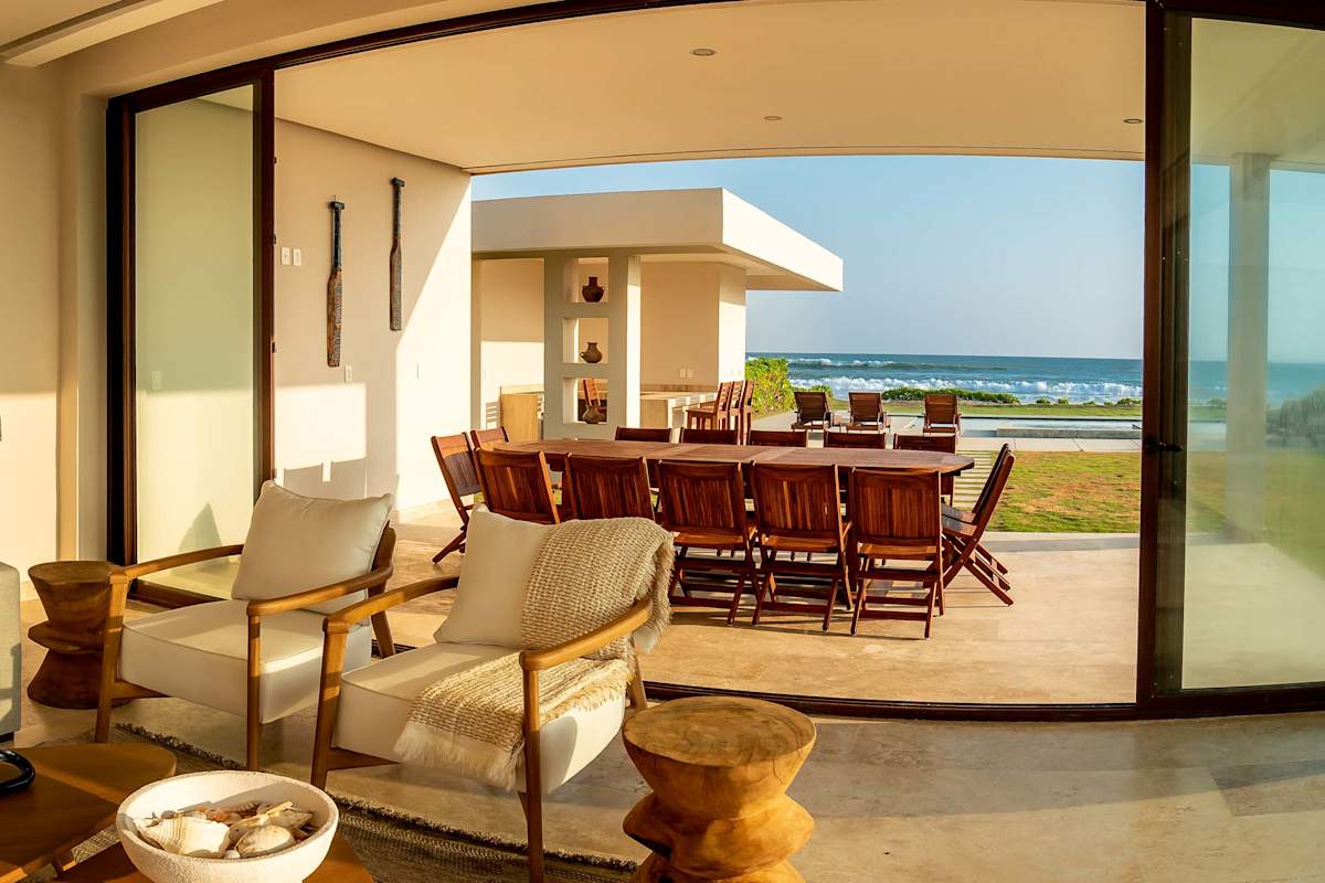 Chic indoor-outdoor lounge with woven rattan chairs and a terrace that frames panoramic ocean vistas