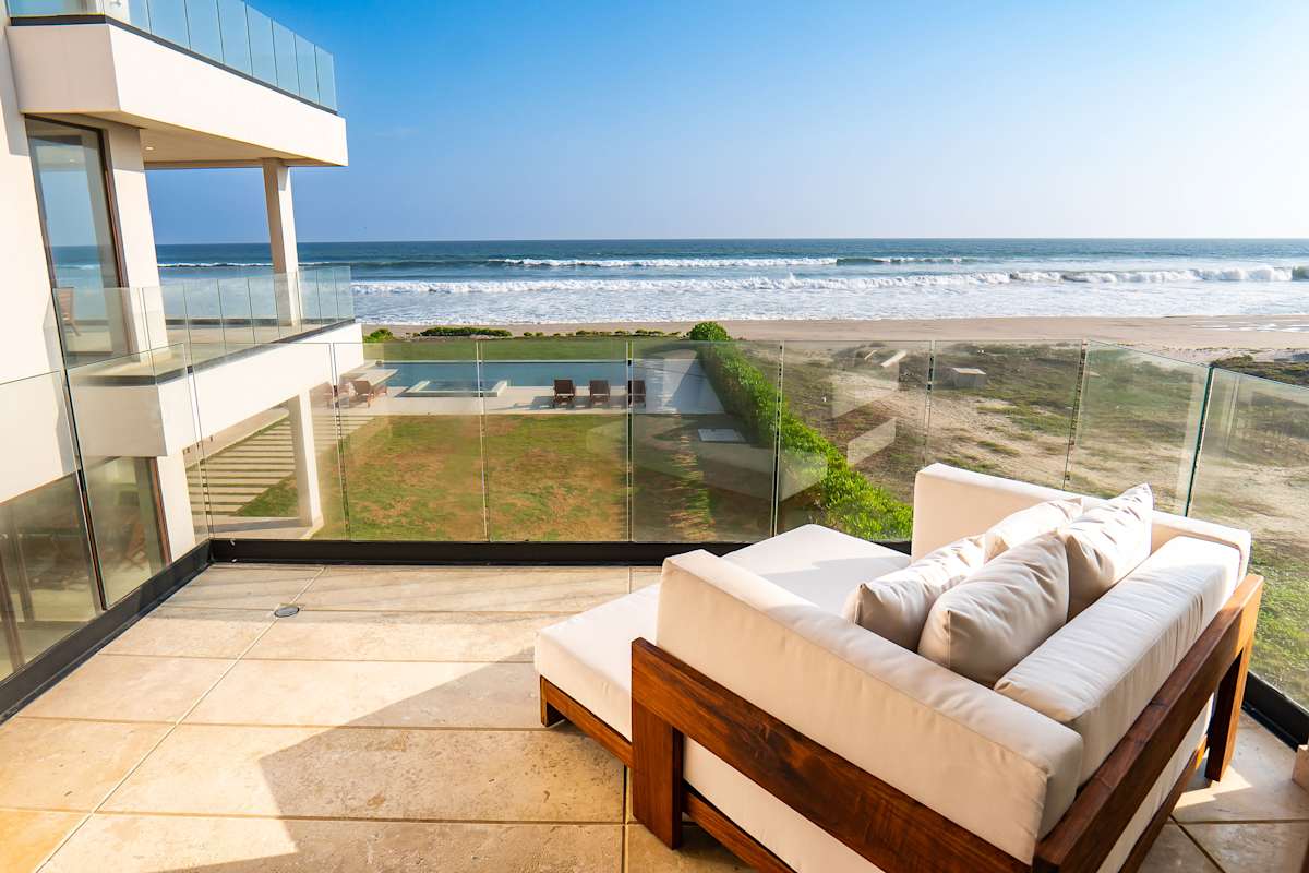 Private oceanfront terrace off Bedroom 2 with lounge seating, beach access, and endless Pacific views