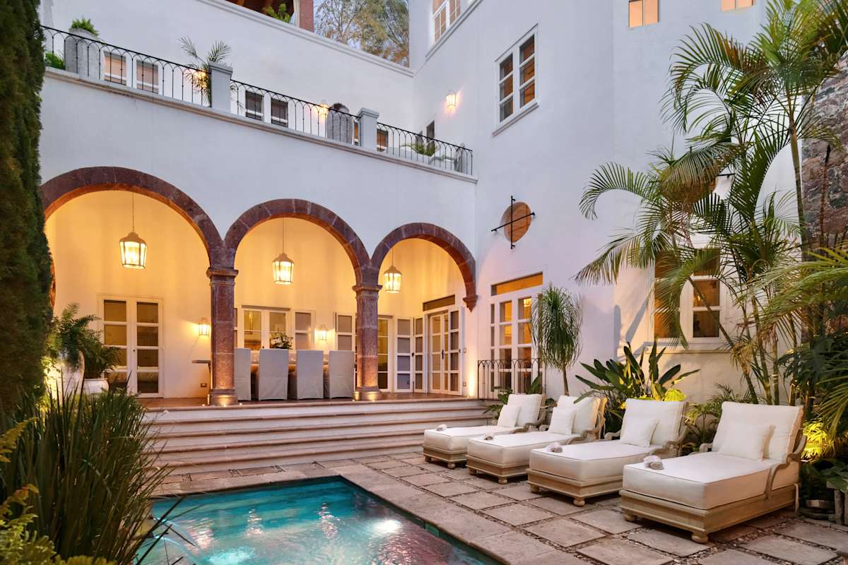 Courtyard pool with lounge seating, lit up in the evening