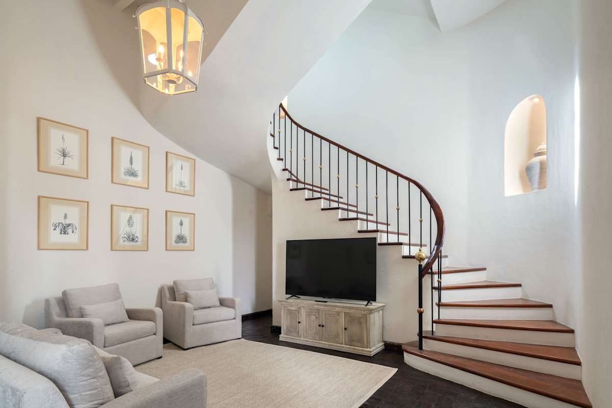 Living room with smart TV beneath a curved staircase