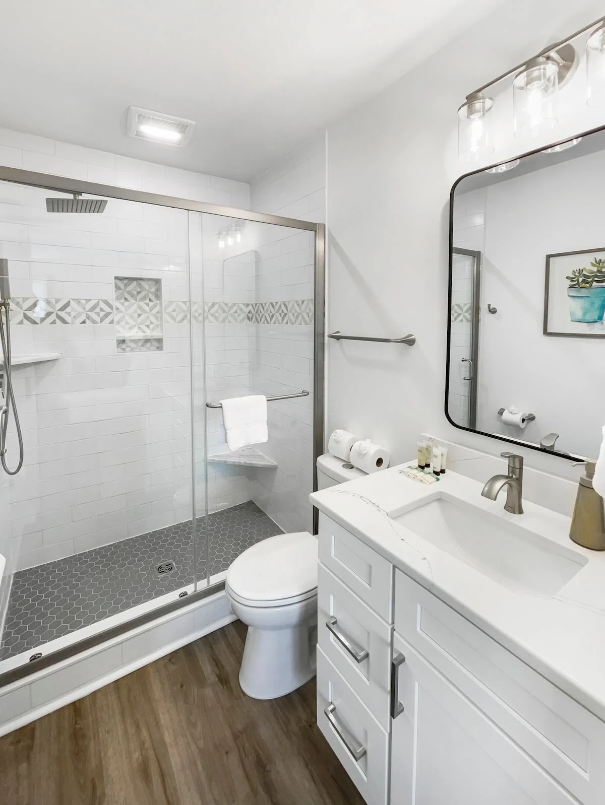 A clean and modern bathroom with a glass shower, white sink, and toilet.