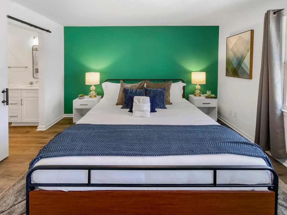 A wide view of a hotel room with a large bed, two nightstands, and a doorway to the bathroom.