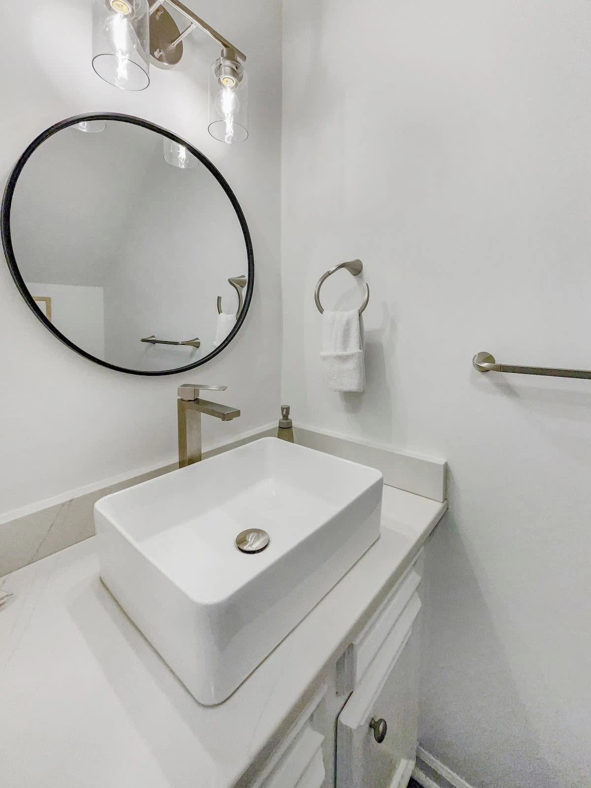 A clean bathroom with a white sink, round mirror, and silver faucet.