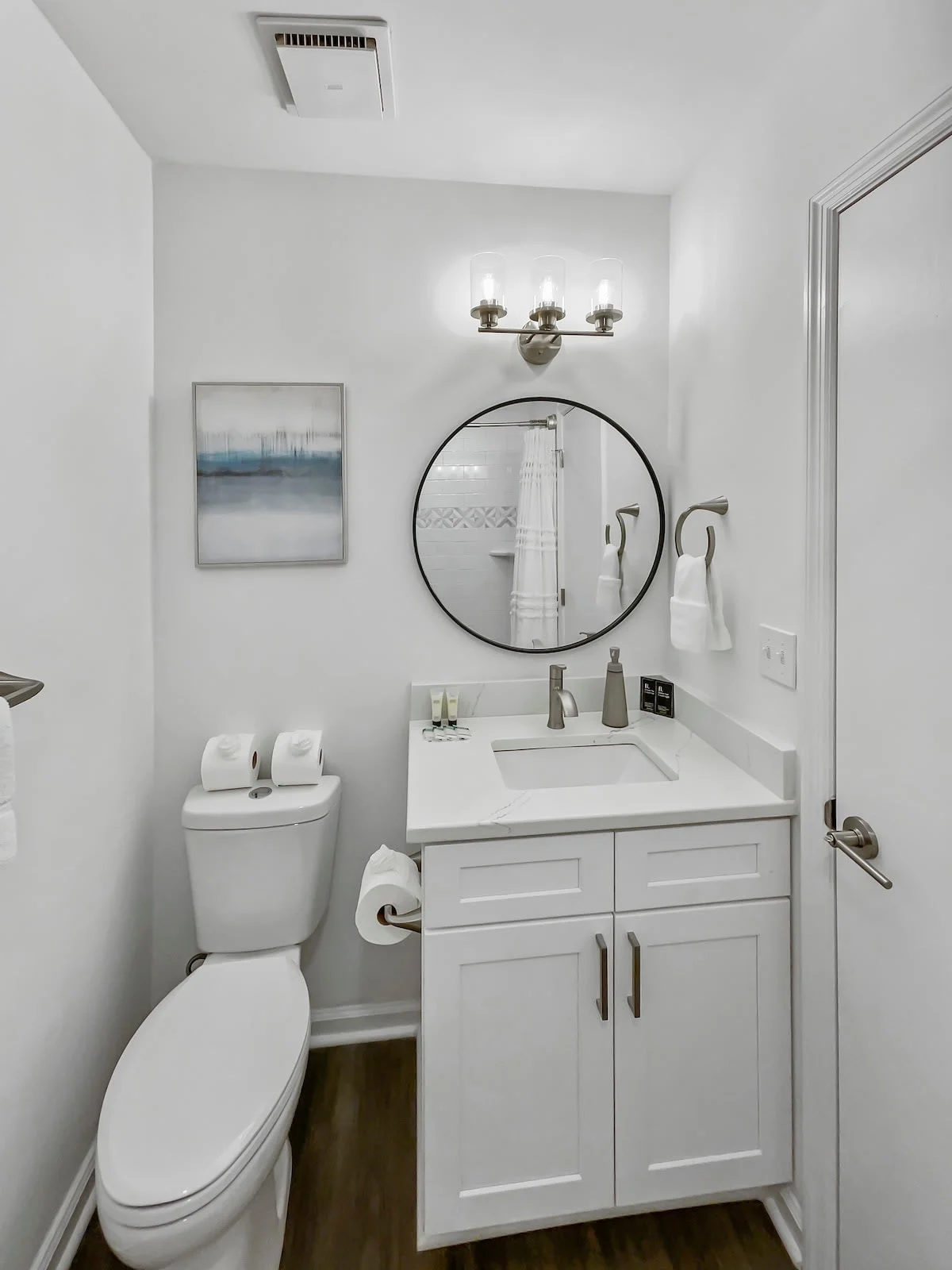 A clean and modern bathroom with a toilet, sink, and mirror.