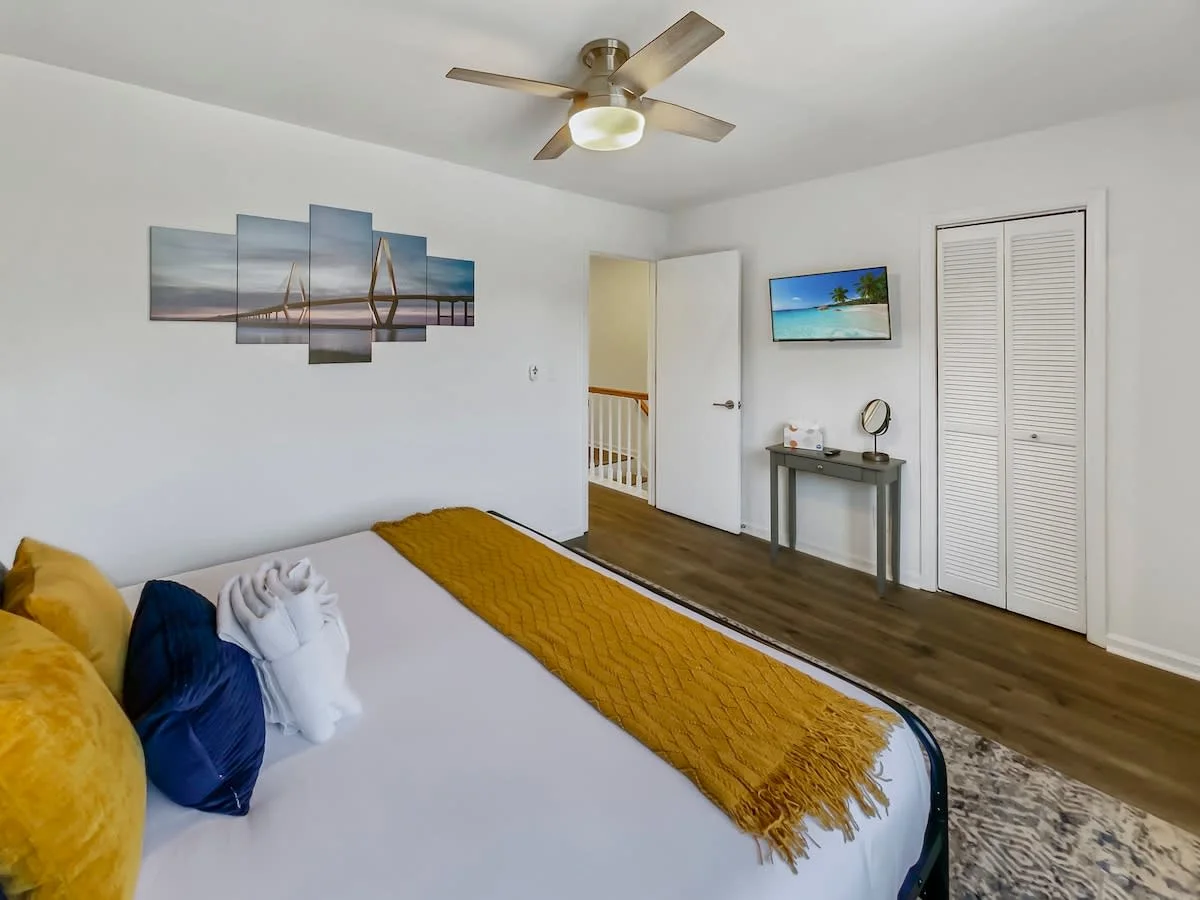 A wide view of a hotel room with a bed, closet, desk, and TV.