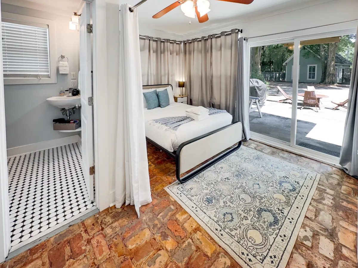 A bedroom with a bed, bathroom, and sliding glass door leading to an outdoor area