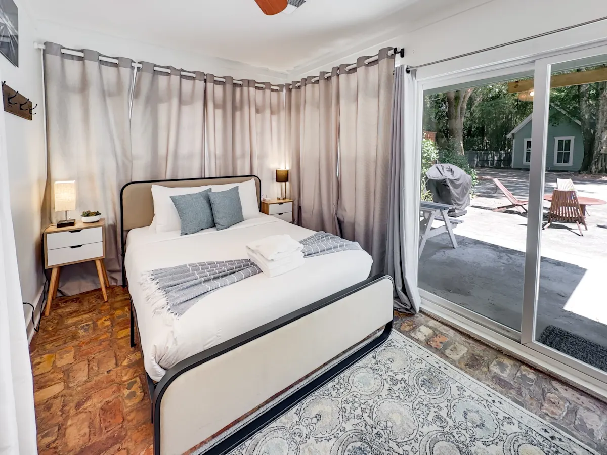 A bedroom with a bed, nightstands, and a sliding door leading to an outdoor area.