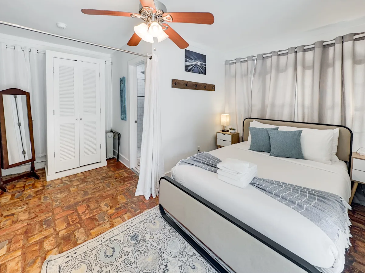A bedroom with a bed, ceiling fan, and curtains