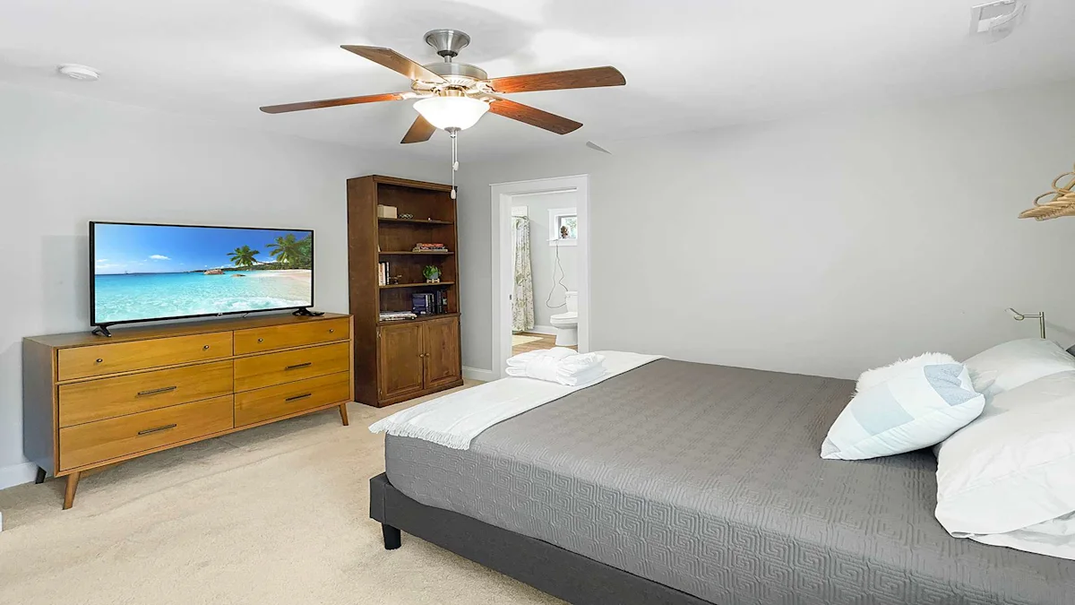 A hotel room with a large bed, TV, dresser, and bookshelf.
